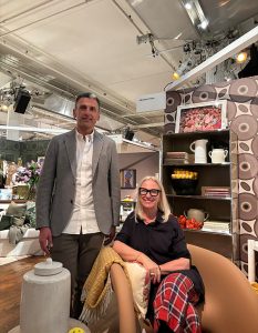 Guests pose in a cozy showroom setting filled with patterned decor, styled shelving, and vibrant floral arrangements.