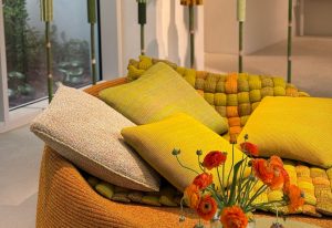 Bomboca brings a burst of texture and color through its basket-woven form and vibrant yellow and green pillows. This playful, cozy piece adds character to any space with its organic, tactile design and inviting shape.
