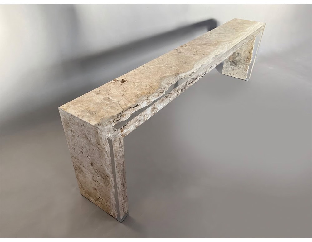 A long Rapolano travertine console table with a raw-edge top partially encased in clear acrylic. The juxtaposition highlights the stone's organic beauty with a modern, sculptural twist.