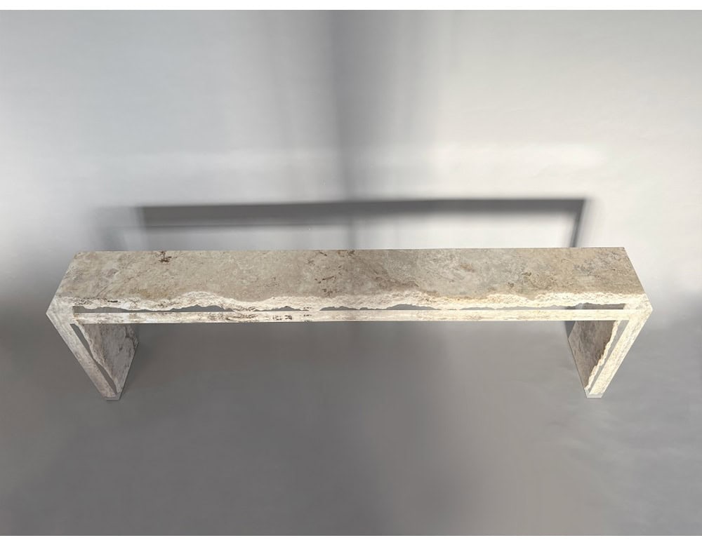 The Rapolano Console Table features a linear travertine slab partially encased in clear acrylic, creating a floating effect that highlights the stone’s raw texture.