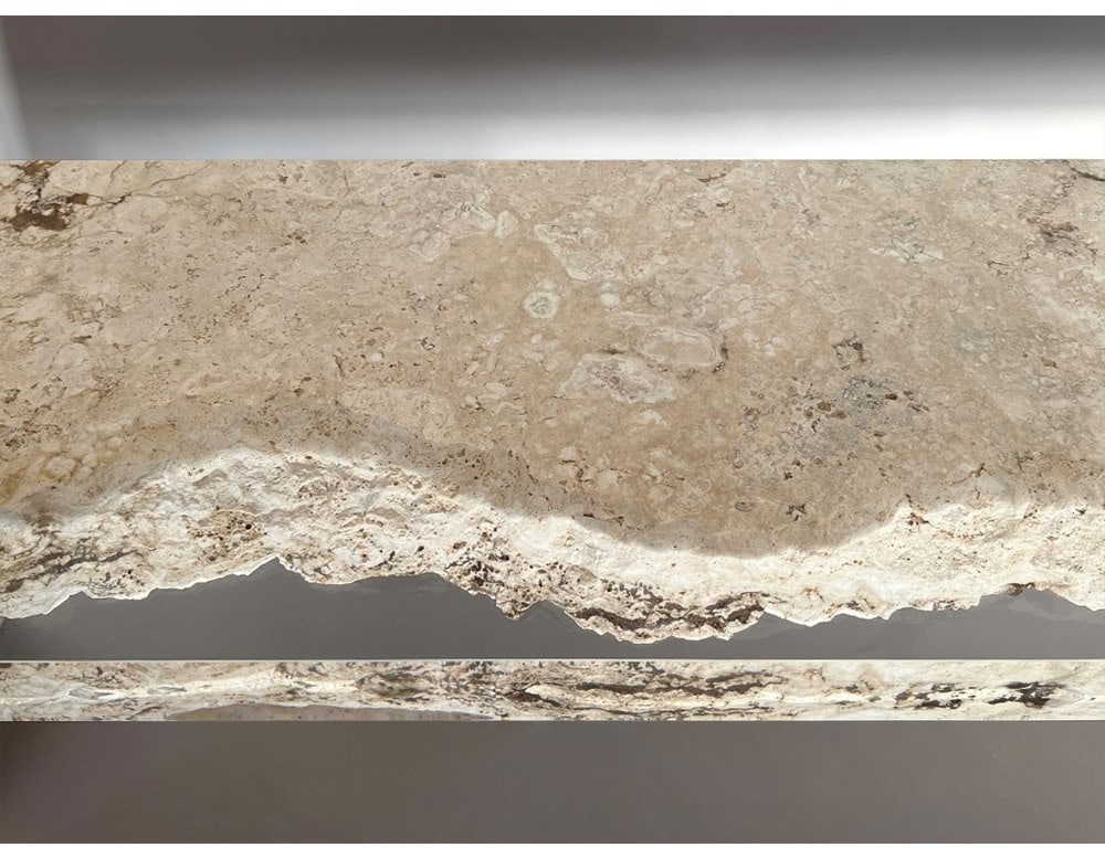 The Rapolano Console Table features a travertine top with rich, natural textures. A clear acrylic layer beneath the stone accentuates its raw, organic edge with a modern, refined touch.