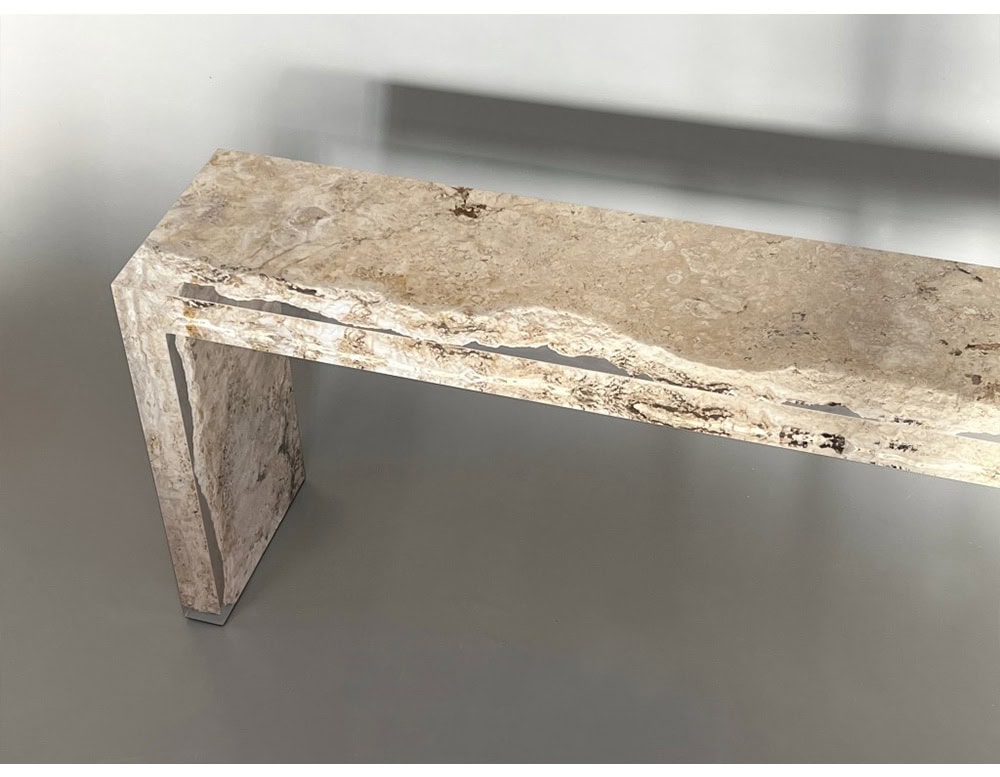 The Rapolano Console Table showcases honed travertine with striking natural textures. Its linear silhouette contrasts with the raw, organic split detailing that runs through the stone.