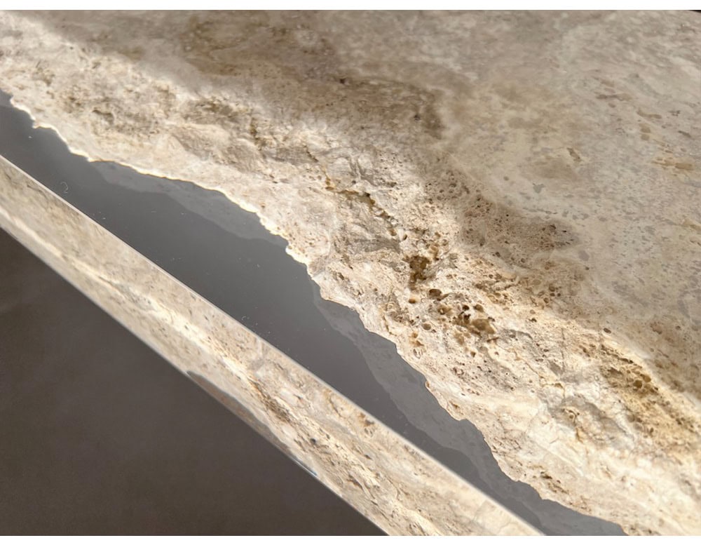 A detailed close-up of the Rapolano Console Table reveals the striking contrast between rough travertine edges and smooth inset acrylic, emphasizing the table’s blend of raw texture and refined craftsmanship.