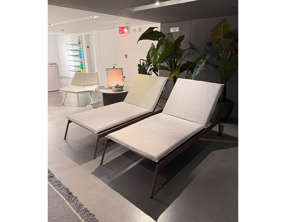 Elegant outdoor loungers with slim bronze frames and light beige cushions. Positioned in a serene indoor garden setting, they evoke comfort and calm with a clean, sophisticated design.