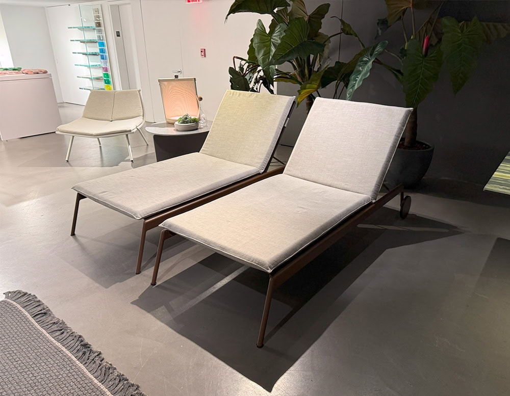 Sleek and minimal, these outdoor lounge chairs offer plush beige cushions and slim bronze-toned frames. Their elegant form invites relaxation in a refined natural setting.