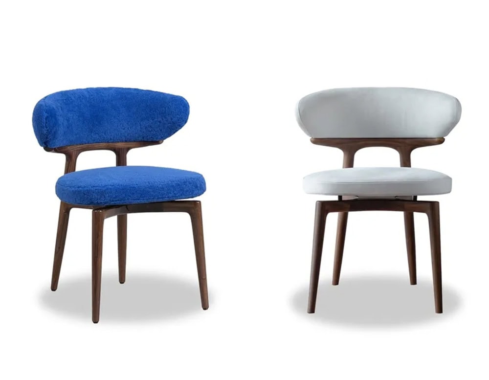 The Bax Clotilde Chair presents a bold silhouette with plush upholstery in cobalt blue and soft grey. Its sculpted wooden base adds an elegant touch, making it a standout piece in modern interiors.