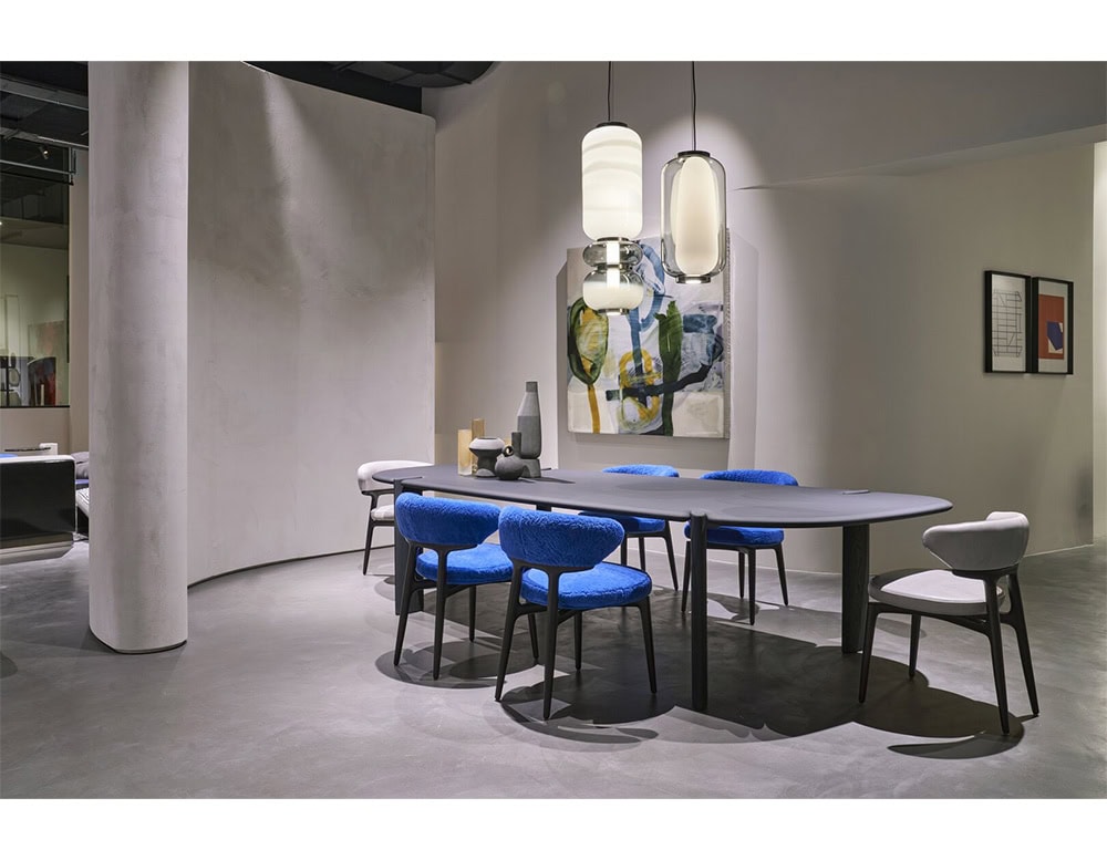 The Bax Clotilde Chair energizes the space with cobalt blue textures and sculpted wood frames. Paired with a sleek dining table and bold art, it creates a dynamic yet refined environment.