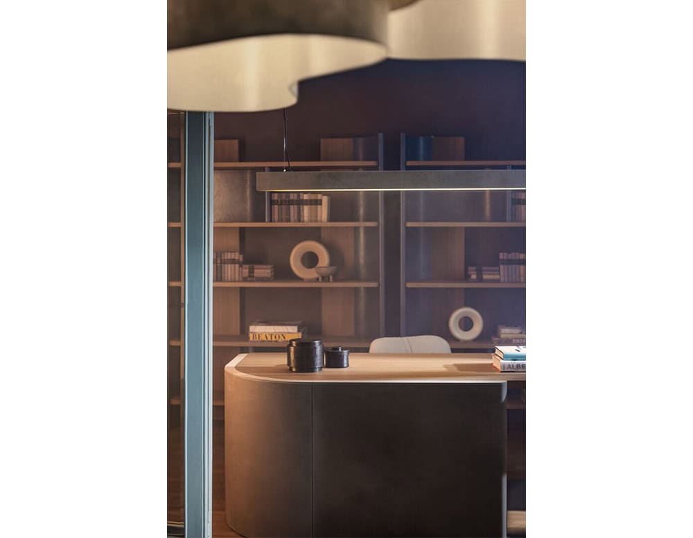 A Bax Joni console with a softly curved base and light wood top, set against built-in shelving filled with books and sculptural objects.