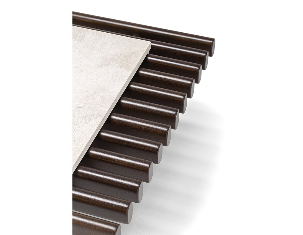 The Ext Elba Coffee Table Outdoor highlights its refined craftsmanship with rounded wood slats and a stone accent, blending tactile materials for a sophisticated outdoor statement.