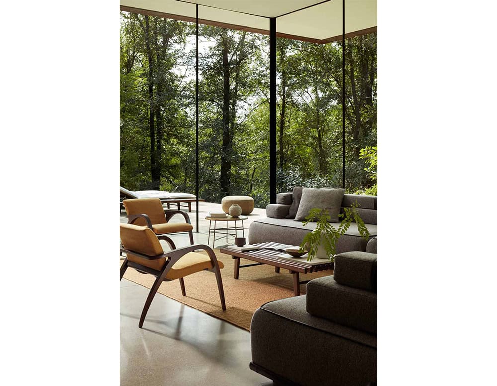 The Ext Elba Coffee Table Outdoor anchors an elegant outdoor lounge with its slatted wood design, seamlessly blending into a nature-inspired setting of soft seating and panoramic views.