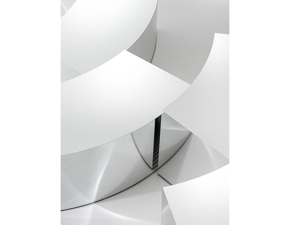 An abstract close-up of the GR Arch Coffee Tables highlights their polished stainless steel finish and curved architectural forms, creating a sculptural interplay of reflections and geometry.