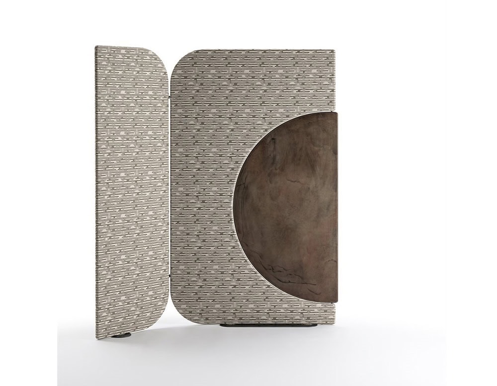 The Enso Screen combines a taupe geometric textile with a rotating wood insert in a deep brown tone. Its circular cutout creates dynamic visual movement, adapting to different room layouts and compositions.