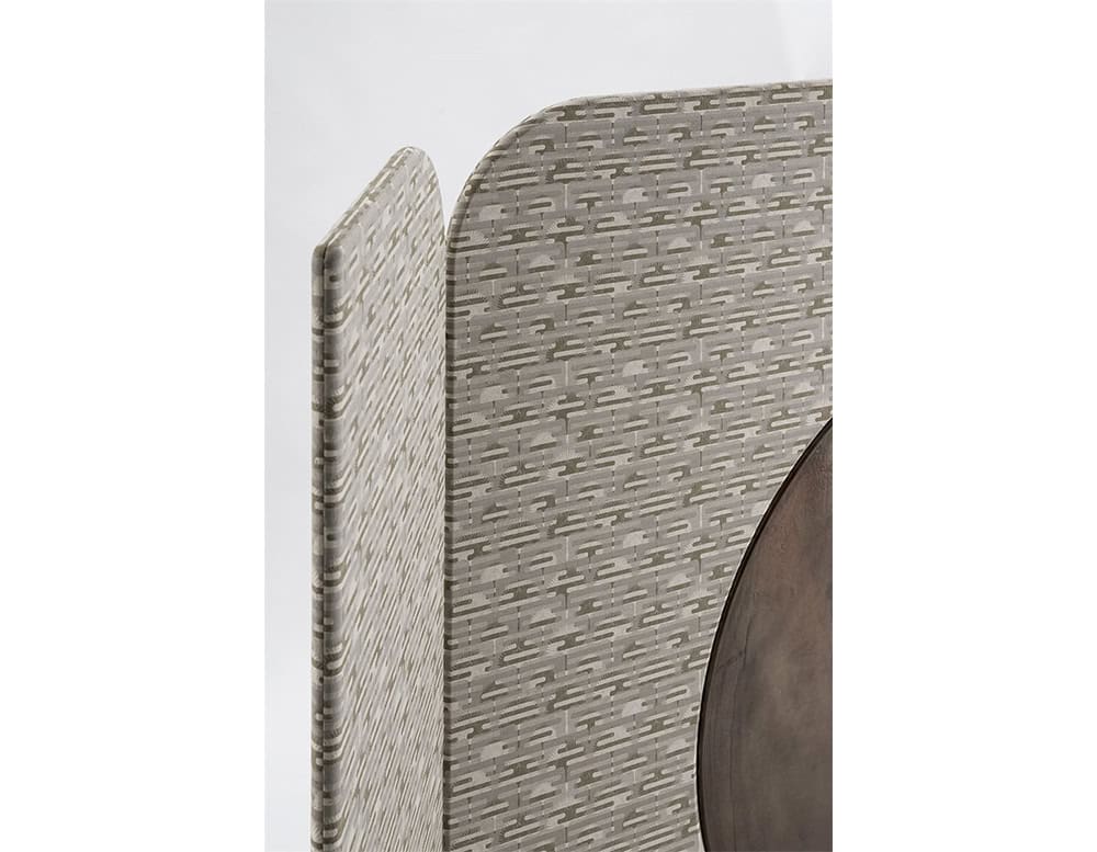 The Enso Screen features curved panels in a patterned taupe textile and a circular wooden insert in dark brown. The mix of materials creates subtle contrast while maintaining a soft and harmonious palette.