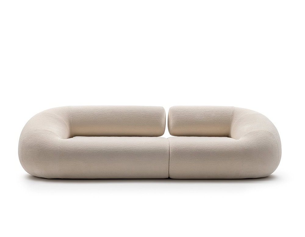 An Evolis Next Sofa in a soft neutral hue, designed with seamless modular elements. Its voluminous form and rounded edges create an inviting, contemporary silhouette perfect for modern lounging.