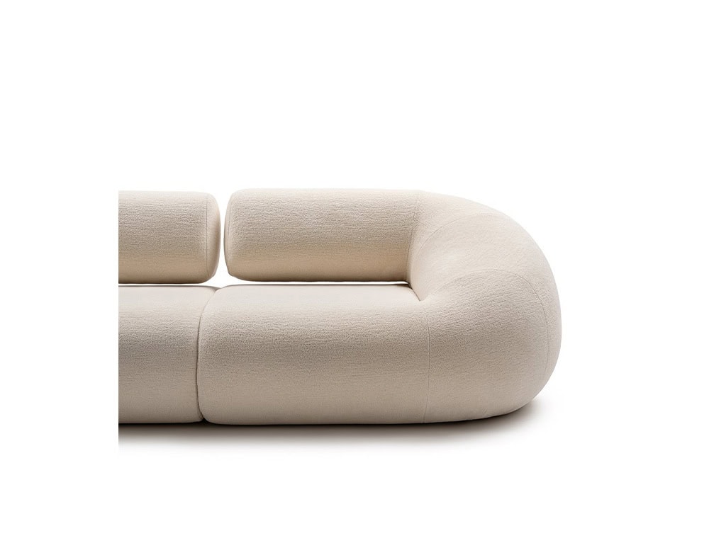 An Evolis Next Sofa showcasing its rounded contours and seamless upholstery. The soft, pale fabric highlights the piece’s sculptural elegance and modular design.