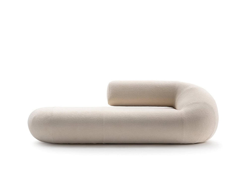 A single Evolis Sofa module with its distinctive cylindrical form and sculptural backrest. The fabric is in a pale, neutral shade with a soft texture that complements its minimalist design.