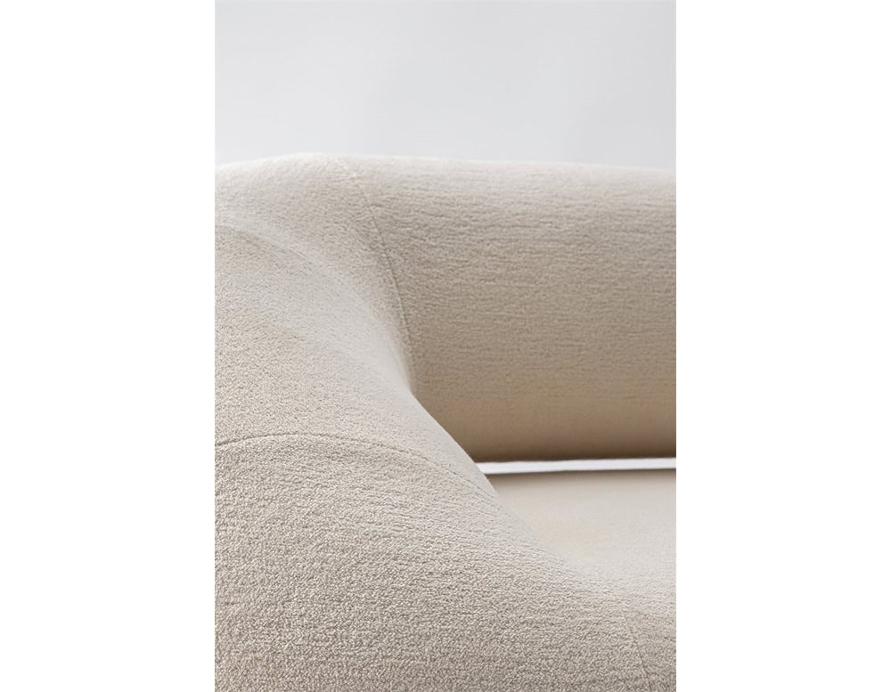 A close-up of the Evolis Sofa’s interior corner, emphasizing its smooth curves and meticulous stitching. The light-textured fabric wraps seamlessly around the sofa’s rounded form, creating an inviting and refined appearance.
