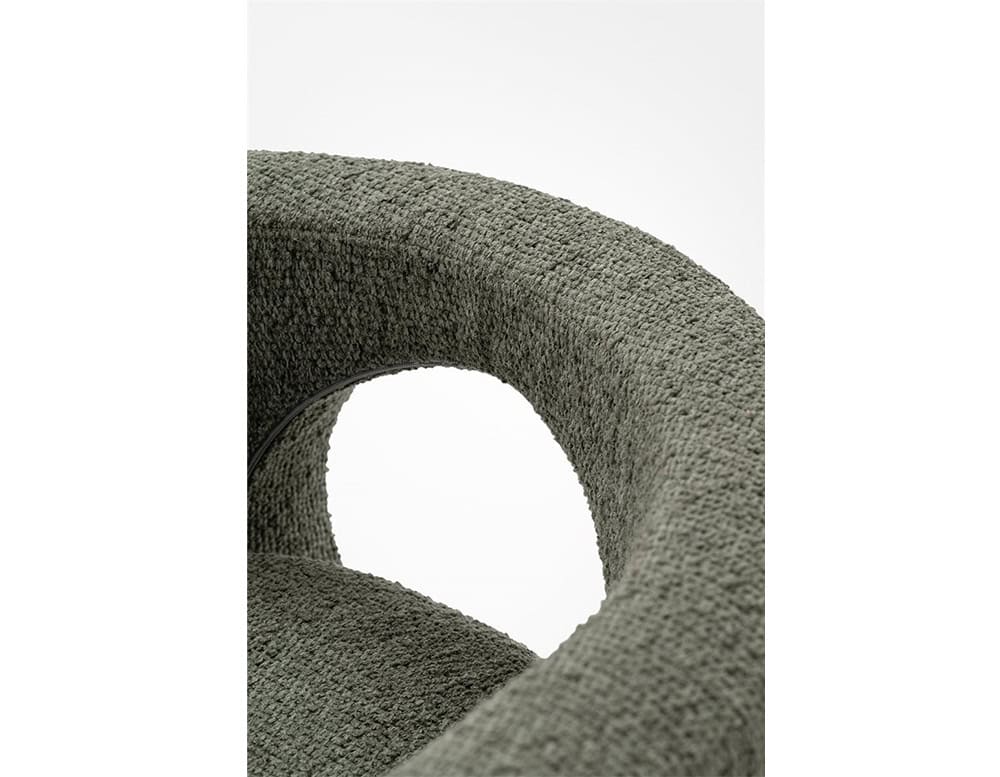 A close-up of the GR H2O Lounge Chair emphasizes its rounded backrest and circular cut-out. The textured upholstery in a muted shade adds tactile interest to the sculptural design.