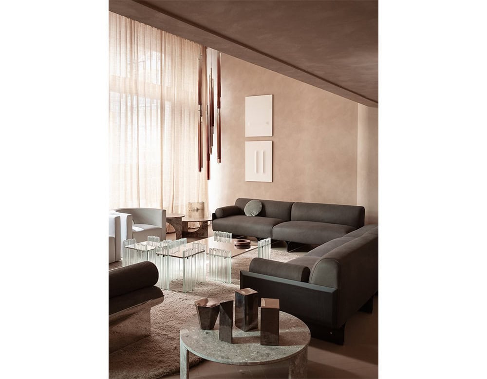 A lounge setting featuring the GR H2O Lounge Chair alongside low-profile modular sofas and sculptural glass tables. The upholstery and surrounding elements are in soft, neutral tones that create a cohesive, serene atmosphere.