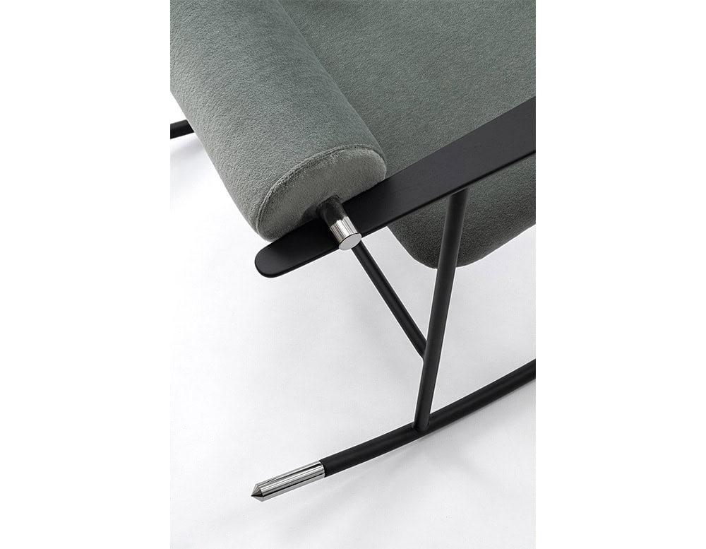 Lou Lou Rock Chair close-up. The image highlights the plush green upholstery, matte black metal frame, and polished chrome details on the armrest pivot and rocker tips.