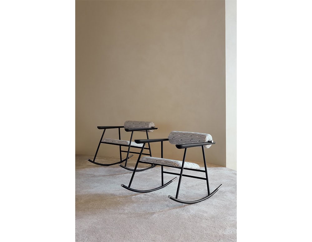 Lou Lou Rock Chair setting. Two chairs with patterned light grey upholstery and matte black frames sit side by side on a soft beige carpet, framed by a neutral wall backdrop.