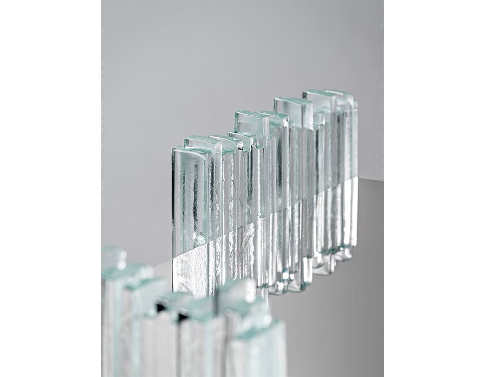 GR Mirage Coffee Table detail view highlighting the clear glass rod legs and their textured edges. The mirrored top reflects the glass elements, creating a layered and luminous visual effect.