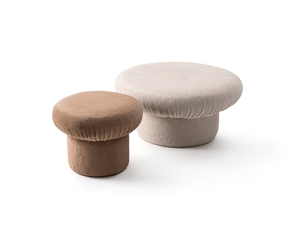 Two GR Nala Stools are shown side by side. The smaller stool is taupe, the larger one is beige, both set against a clean white background. Their rounded cushioned tops and soft textures give a plush, cozy appearance.
