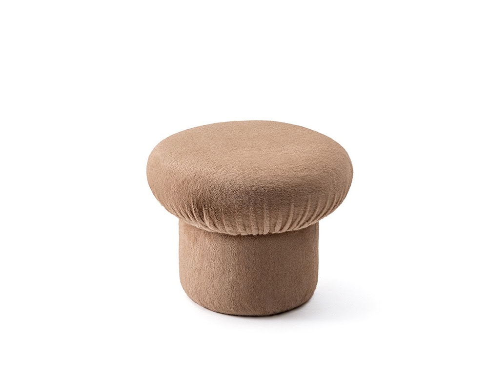 The GR Nala Stool features a soft taupe color with a plush, rounded cushion top. Set against a white background, its cozy silhouette and textured fabric convey comfort and simplicity.