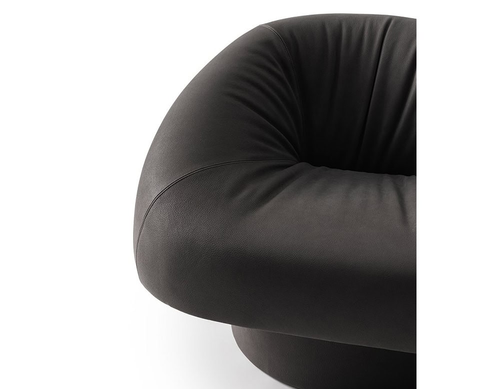 The GR Olivia Chair, captured here in a detailed close-up, emphasizes its plush contours and the subtle grain of its dark leather upholstery, highlighting its enveloping silhouette and luxurious comfort.