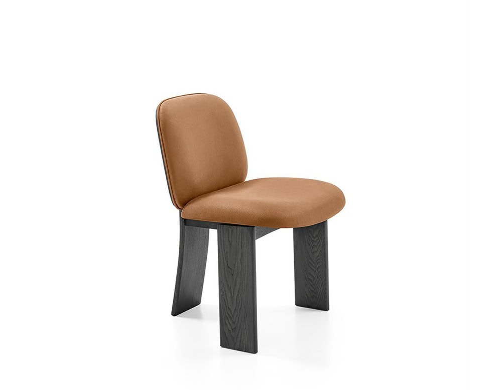 The GR Saki Chair presents a sculptural silhouette with softly curved camel leather upholstery. Its substantial black wood legs, gently flared at the back, add a grounded architectural elegance to the design.
