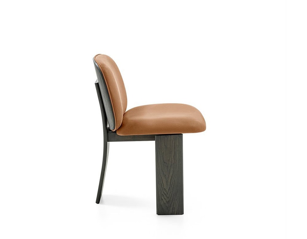 The GR Saki Chair features a soft camel leather seat and backrest, paired with a sculptural black wood base. Its side profile reveals a subtle backward curve, highlighting the chair's ergonomic and architectural elegance.