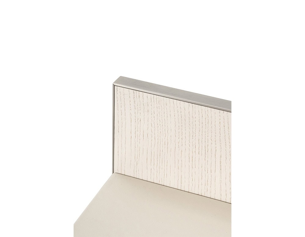 The GR Stresa Console Table detail reveals a close-up of its textured wood back panel in soft ivory tones, framed in brushed metal, paired with a smooth, matte-finished surface.