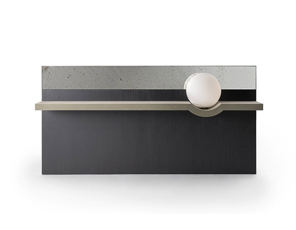 The GR Stresa Mirror combines a smoked reflective surface with a dark wood panel and a champagne-toned shelf. A glowing glass sphere rests in the shelf’s carved curve, offering subtle lighting and architectural balance.