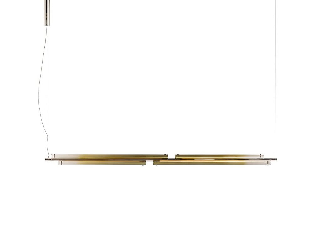 The GR Tratto Suspension Light creates a floating linear rhythm overhead. Its warm metallic surface reflects soft, amber tones, contributing a delicate luminosity to the minimal environment.