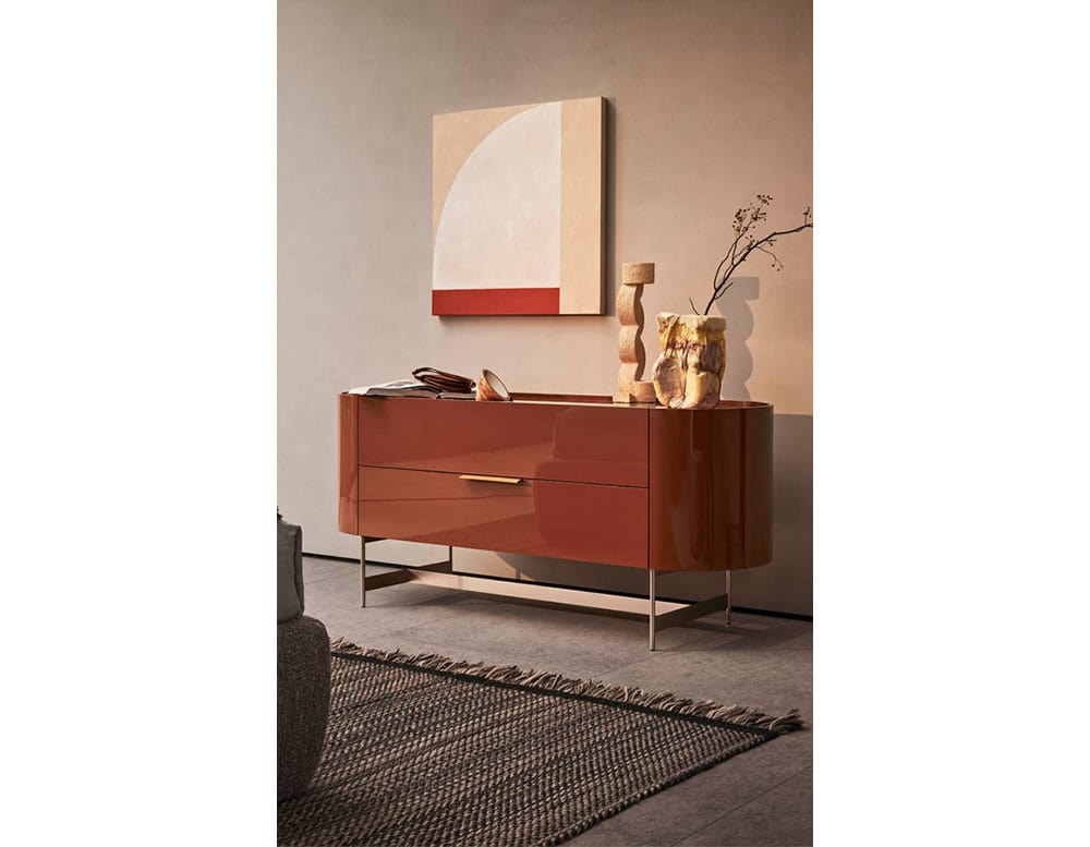 The Pian Dedalo Nightstand stands out in a bold lacquered red finish with smooth curves and sleek metal legs, perfectly styled with sculptural objects and geometric art for a modern statement.