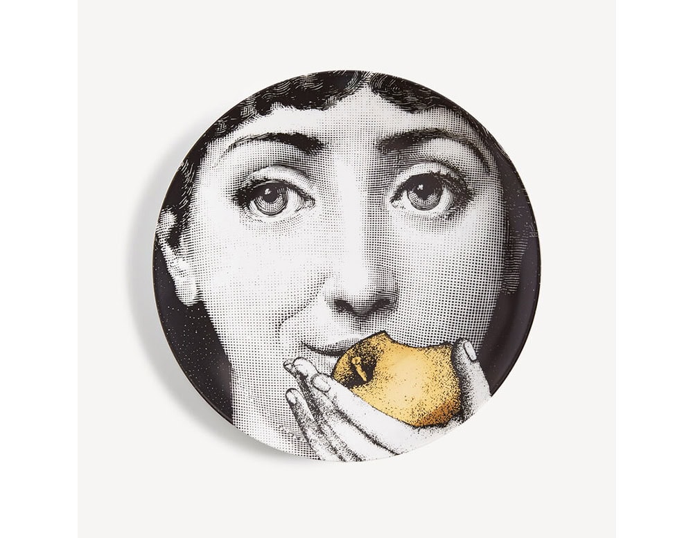 Decorative plate with a black and white face holding a golden apple. A bold mix of classic portraiture and surreal detail in a compact design.