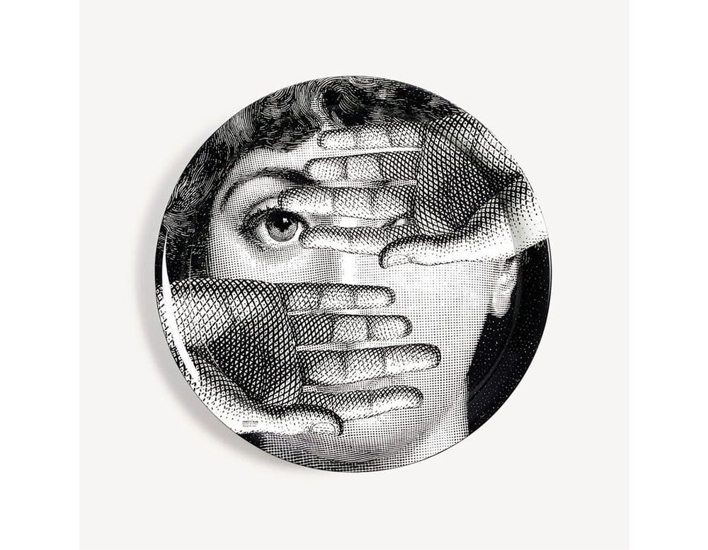 Black-and-white porcelain tray depicting a mysterious face framed by gloved hands. The composition evokes curiosity and playful secrecy in a surreal, cinematic style.