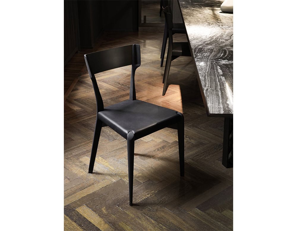 The Hen Chair VA showcases clean lines and solid craftsmanship. Its matte black finish and curved backrest offer both comfort and sculptural appeal, making it an ideal choice for refined dining settings.