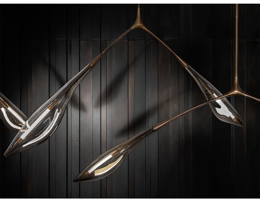 A sculptural ceiling light with bronze branches and glass shades shaped like leaves. Its organic silhouette and soft illumination make it a striking centerpiece in refined interiors.