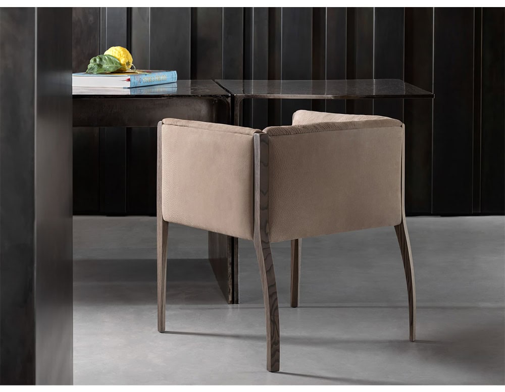 The Hen Shelly Chair features soft neutral upholstery with a relaxed form, framed by elegant wooden legs in a natural finish that complement its inviting silhouette.