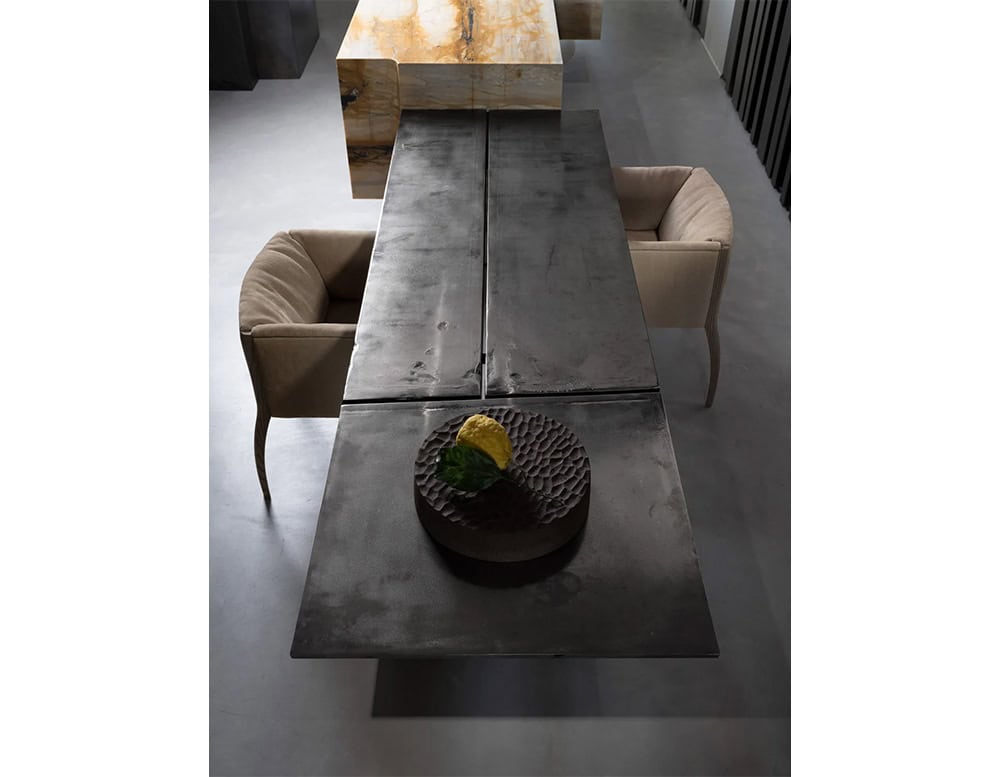 The Hen Shelly Chair pairs sculpted wooden legs with a curved, upholstered seat in a warm neutral tone, offering comfort and balance to the striking black dining table.