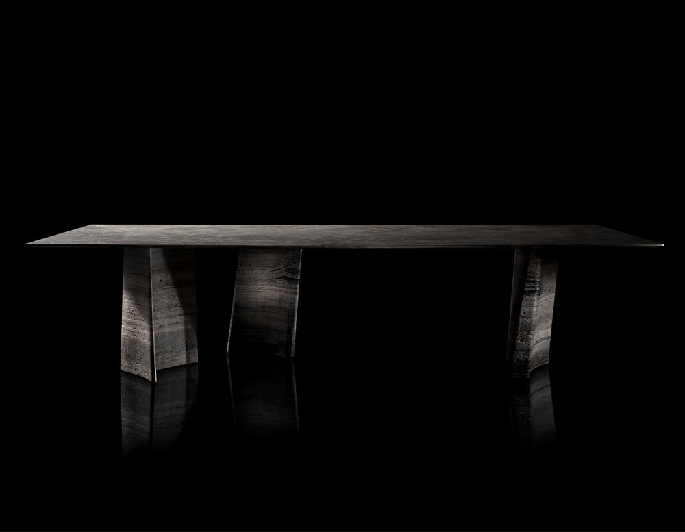 Hen Sisma Dining Table features a dark sculptural base formed by three angular elements that support a sleek top, combining architectural balance and modern elegance.