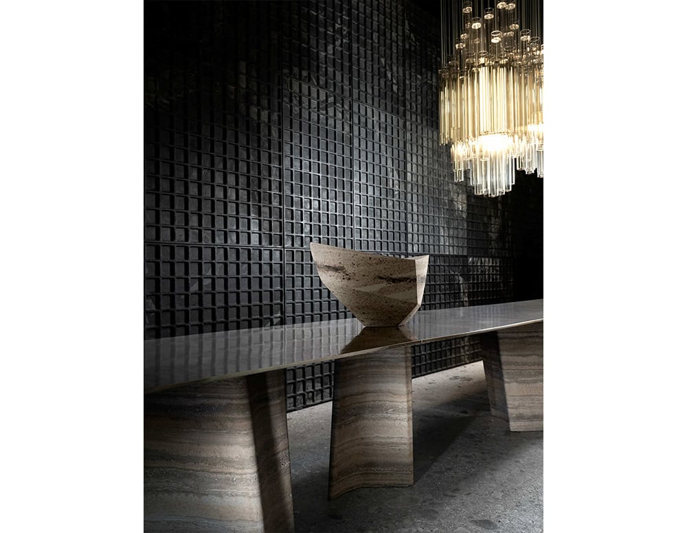 A sculptural dining table featuring layered stone legs and a highly polished top. The natural textures add depth while the minimalist form keeps the focus on material and craftsmanship.