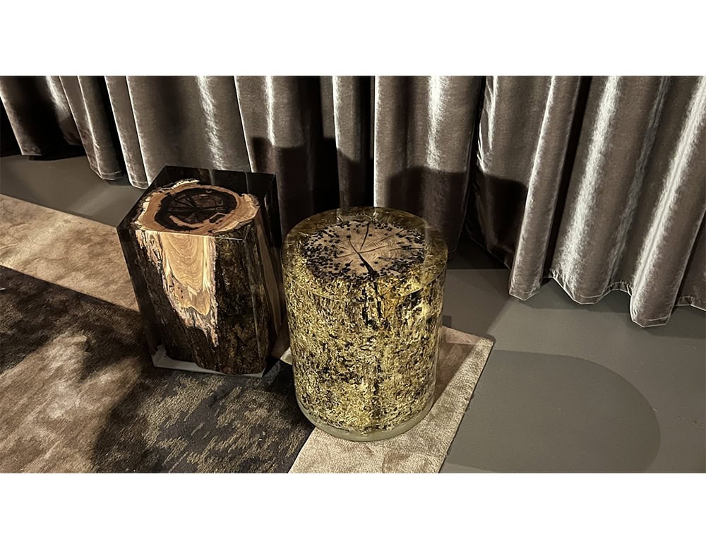 Two sculptural stools showcasing organic materials in resin. One highlights golden moss textures, the other a section of petrified wood. Artful and raw, perfect as statement seating or accent tables.