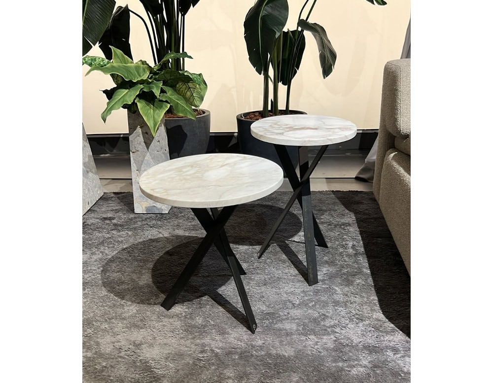 Set of two round coffee tables with white marble tops. Each features sleek black metal legs in a crisscross design, adding contrast and elegance to modern interiors.