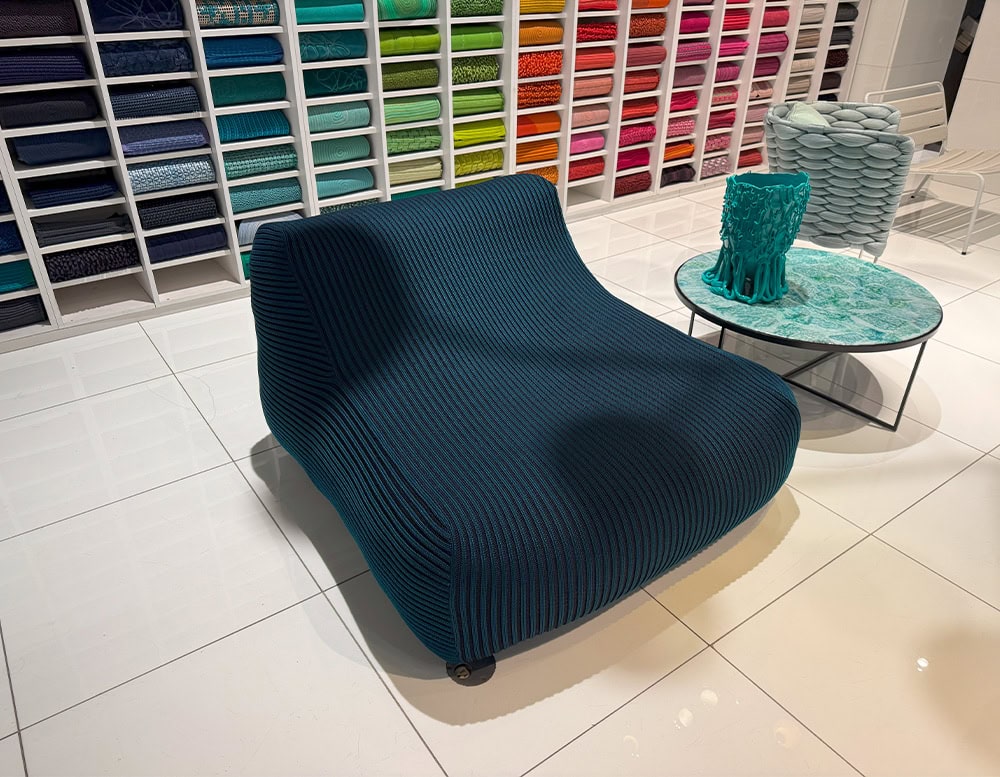 Sculpted lounge chair in rich navy with teal ribbing. Its fluid form and bold texture bring a playful yet modern touch to outdoor lounging spaces.
