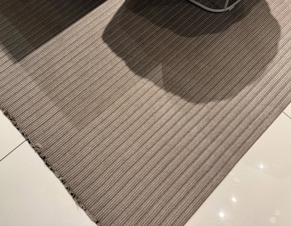 Durable high tech outdoor rug featuring a ribbed texture in neutral tones that pairs style with functionality for any exterior setting.