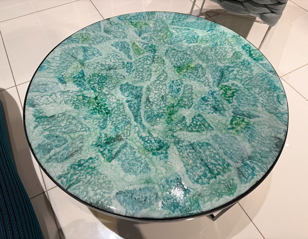 Close-up of vibrant blue glass top. The handcrafted surface displays fluid, organic patterns with rich texture and coastal hues.