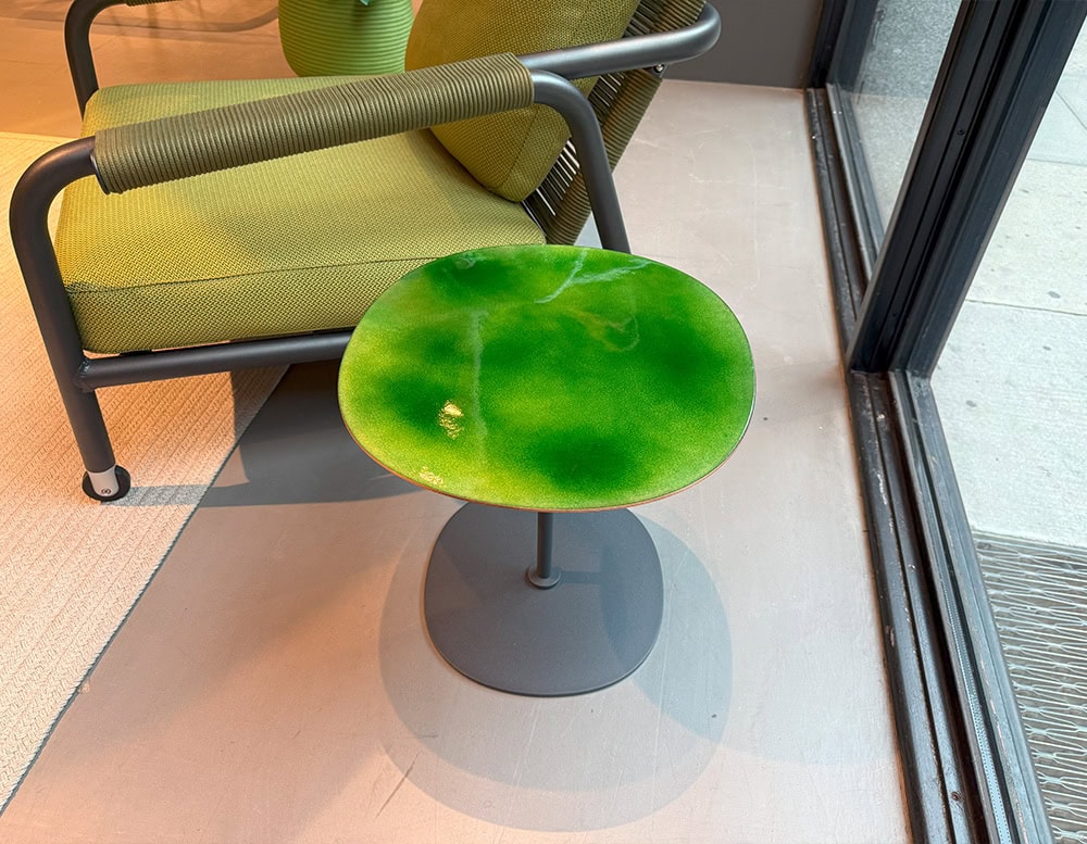 Compact side table with a vivid green enamel top. The organic shape and glossy finish add a fresh accent to any outdoor lounge setup.