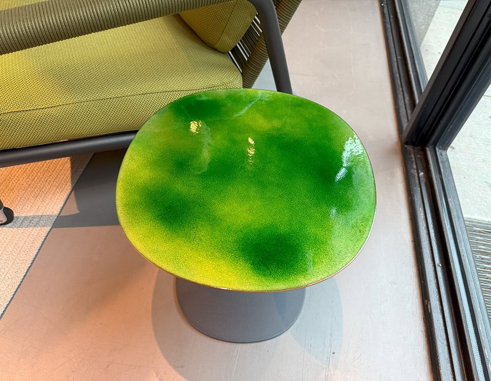Green enamel side table with a rounded square top and soft gloss. Its bold color and sculptural silhouette make it ideal for stylish outdoor settings.